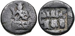 Coin of the Panchalas of Ahichhatra (75-50 BCE). Obv Indra seated facing on pedestal, holding bifurcated object. Rev Idramitrasa in Brahmi, Panchala symbols.