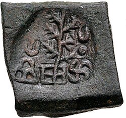 A coin of Takshashila, portrays a tree flanked by a hill surmounted by a crescent and a Nandipada above a swastika.[26]