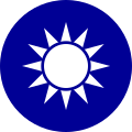 A blue circular emblem on which sits a white sun composed of a circle surrounded by 12 rays.