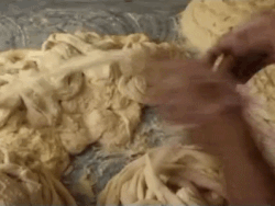Act of stretching a dough into multiple layers by hand