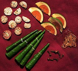 Display of the items usually included in a chewing session: The betel leaves are folded in different ways according to the country and most have a little calcium hydroxide daubed inside. Slices of the dry areca nut are on the upper left hand and slices of the tender areca nut on the upper right. The pouch on the lower right contains tobacco, a relatively recent introduction.