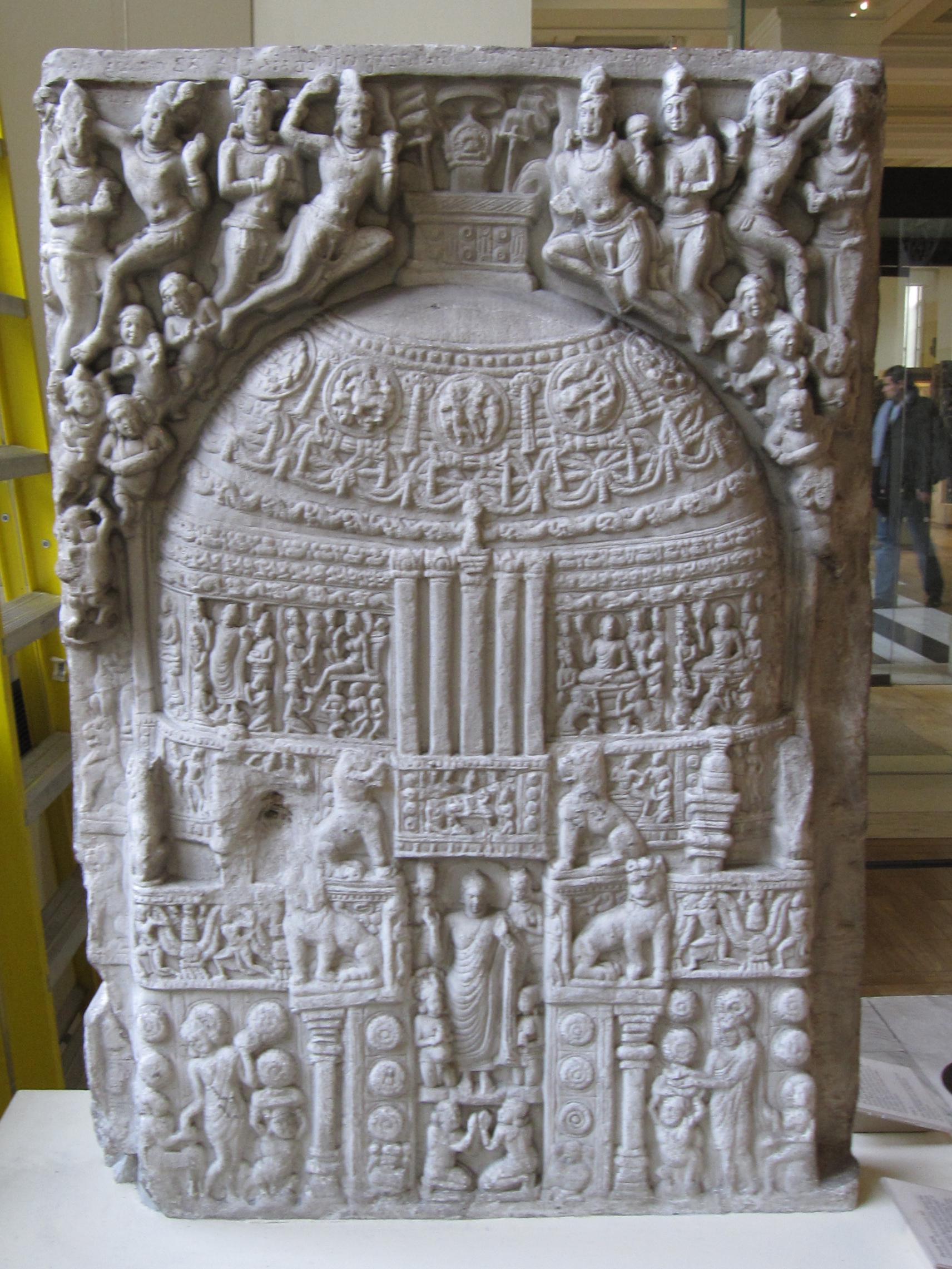 Drum slab. Limestone, 3rd century CE. This slab was first carved in about the 1st century BCE. When the Great Stupa was refurbished under the patronage of the Satavahana rulers beginning in about the 2nd century CE, the slab was turned over and carved on this side with a Buddha figure within the stupa. Side B: The Great Stupa at Amaravati with the Buddha standing in human form in the entrance to the monument. It is now in the British Museum.